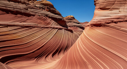 Striated rock formation in light orange and brown hues, with a clear blue sky. Symbolic of natural textures, arid landscape, geological wonder, earth tone