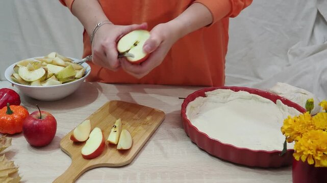 A girl is making apple pie at home. Autumn fall baking background with pumpkins, apples, nuts, food ingredients and seasonal spices. Cooking pumpkin or apple pie for Thanksgiving and autumn holidays, 