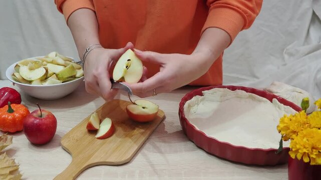 A girl is making apple pie at home. Autumn fall baking background with pumpkins, apples, nuts, food ingredients and seasonal spices. Cooking pumpkin or apple pie for Thanksgiving and autumn holidays, 