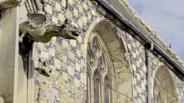 Gothic gargoyles and flint-limestone checkerboard wall of Saint-Martin Church, Saint-Valery-sur-Somme, Picardy, with ornate tracery, lancet windows and slate roof details under a bright autumn sky