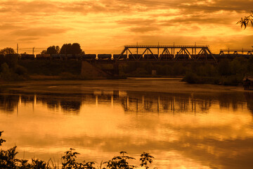 Freight Train Carrying Oil Products Crossing Railway Bridge at Sunset