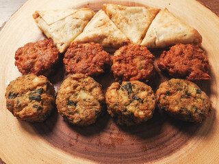 Indian style starter food selection of samosa, bhajis and pakoras on wooden board background. Party sharing finger food variety made from fine products and aromatic spices. Special orient vibe.