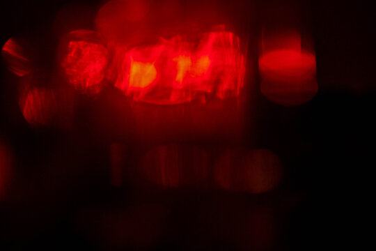 A blurry image of red lights and a yellow light. The red lights are scattered throughout the image, creating a sense of movement and energy. The yellow light is in the center of the image - Powered by Adobe