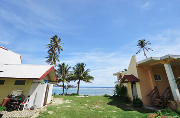 Tropical Seaside Houses with Palm Trees and Bright Blue Sky © Loginova