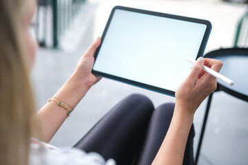 Woman hand working on blank white screen digital tablet in coffee shop.