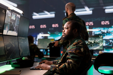 Officer in command center planning, analyzing and gathering information on enemy troops. Soldier in...