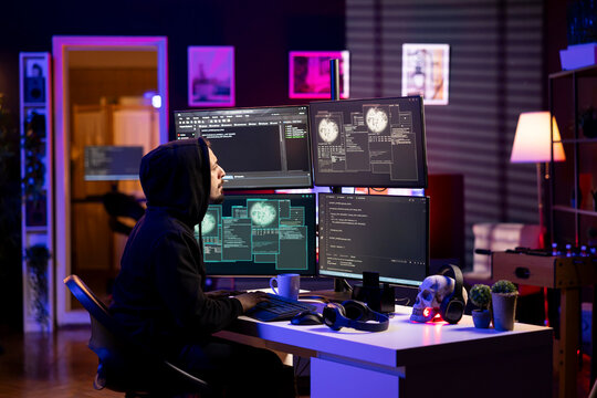 Hooded hacker in neon lit lair using PC to gain unauthorized network access, targeting unpatched connections. Rogue engineer at home bypassing security and exploit servers for stolen data profit