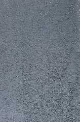 Texture of fresh asphalt showing fine grains and smooth surface under natural light in a pavement construction area