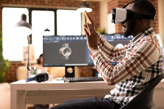 African american freelance developer immersed in VR, prototyping 3D clamp model. Black male engineer using computer aided design tools and virtual reality headset to craft precision product design. - Powered by Adobe