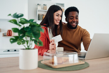 Happy multiracial couple online shopping with credit card