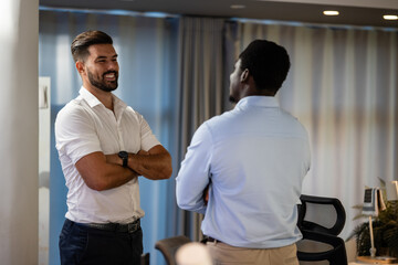 Two businessmen engaged in friendly office conversation