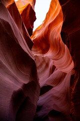 Abstract deep vertical view into Antelope Slot Canyon, highlighting the dramatic contrast of purple and orange sandstone walls.