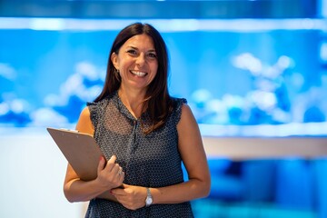 Confident smiling businesswoman holding clipboard indoors