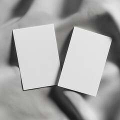 Two blank white textured cards on gray fabric background with soft shadows, minimal stationery mockup for branding and design