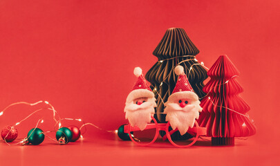 Festive red background with a Christmas tree and cheerful Santa Clauses