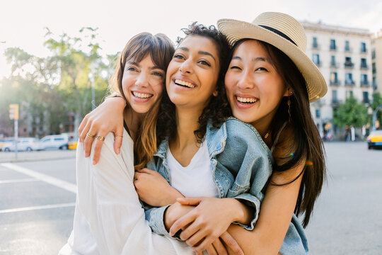 Group of cheerful diverse women hugging in the city. Happy female friends enjoying friendship and togetherness outdoors. Lifestyle and inclusion concept.
