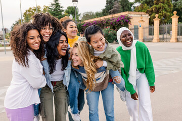 Happy diverse women laughing together in the city. Joyful female friends enjoying time outdoors in a vibrant urban environment. Friendship and happiness concept.