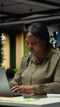 Vertical Video Demotivated businesswoman sighing after realizing the late hour, pushing limits late at night and working alone in the office. Mental haze and troubled by workload, struggling with