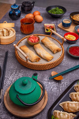 Still life with adapted Christmas spring rolls, filled with turkey and cranberries, served on a gold platter with cranberry sauce and garnished with rosemary