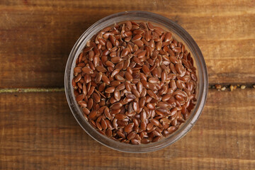 bowl with flax seeds on a wooden background