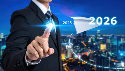 Businessman in suit points at futuristic interface with paper airplane symbolizing progress towards 2026, set against cityscape at night. image conveys innovation and forward thinking