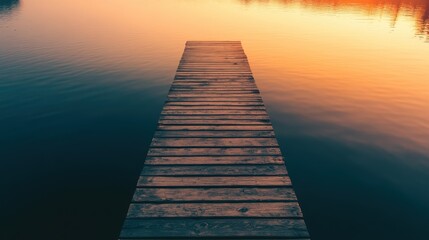 Serene wooden dock extending into calm water during sunset with warm orange and pink hues