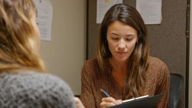 Medium shot of an interview coach providing detailed feedback to a candidate highlighting strengths and areas for improvement after a practice session.