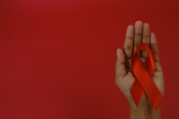 woman Holding Red Ribbon For December World Aids Day Isolated On red Background. Healthcare Concept
