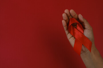 woman Holding Red Ribbon For December World Aids Day Isolated On red Background. Healthcare Concept