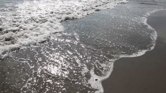 Meeresbrandung auf Vulkansand am Badestrand von Quepos, Puntarenas in Costa Rica.