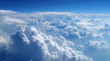 Fototapeta premium Puffy white clouds fill the vast blue sky illuminated by sunlight during a daytime flight. The scene captures the beauty and tranquility found high above the earth.