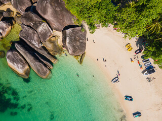 A stunning top-down aerial (flat lay) view of Tanjung Tinggi Beach, Belitung. Giant granite boulders, white sand, and clear turquoise water create a beautiful natural abstract pattern.