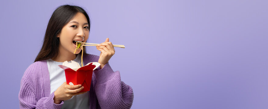 A young woman with long black hair smiles as she eats noodles from a red takeout box. She uses chopsticks and wears a cozy purple sweater, set against a soft purple background.