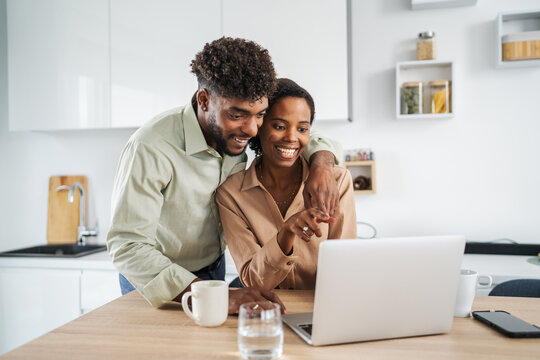 African american couple using laptop computer in kitchen