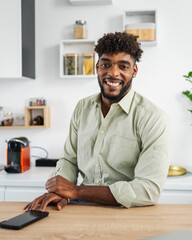 Fototapeta premium Young black man smiling while leaning on kitchen counter