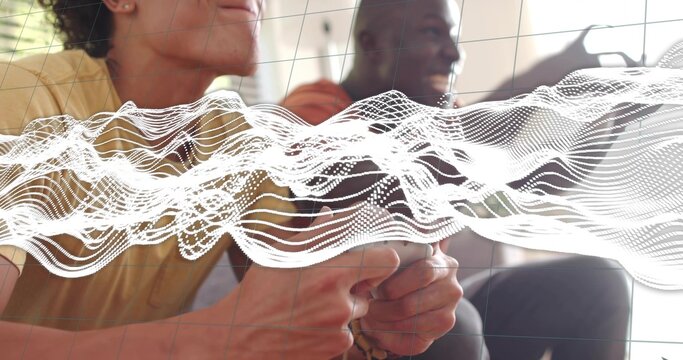 Gripping controller, friends in yellow tee and dark shirt sitting on couch at home showing waveform - Powered by Adobe