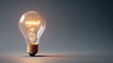 Glowing incandescent light bulb against a dark gray background.
