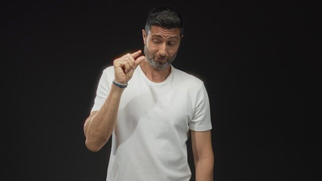 Man showing pinch gesture with thumb and forefinger to indicate tiny size in studio with black setting; skepticism smallness measurement.
