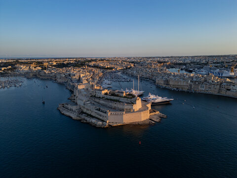 Aerial view of Fort St Angelo at sunset with luxury yachts. Historic limestone fortification in Birgu, Grand Harbour, Malta.