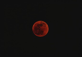 Striking view of a perfectly spherical blood moon during a total lunar eclipse against a black night sky