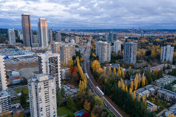 Obraz premium Autumn Cityscape Of Burnaby With High Rise Towers, Rail Line, And Forested Suburbs
