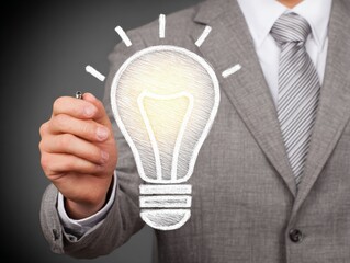 Idea Generation: An executive, dressed in formal attire, draws a radiant light bulb, symbolizing creativity and the spark of invention, signifying intellectual exploration.