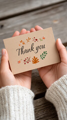 Thanksgiving celebration: close-up of hands holding thank you note with autumn leaves