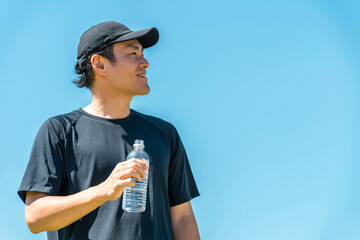 A man drinking water or mineral water during exercise (hydration, exercise, workout, running, walking)

