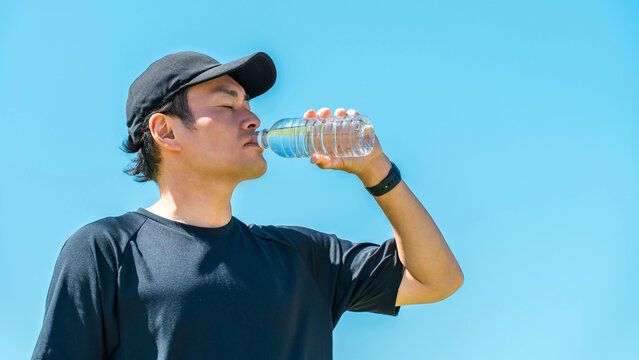 A man drinking water or mineral water during exercise (hydration, exercise, workout, running, walking)

