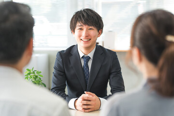 A young Asian businessman and his customer couple serving in a showroom/negotiation space
