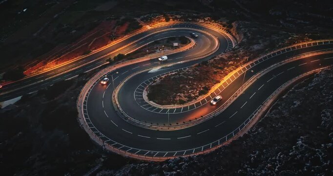 Malta: Cars driving along winding road at sunset, creating a mesmerizing aerial view of transportation infrastructure and scenic landscape. Night traffic in mountains. Drone footage