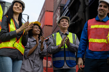 Diverse group of industrial container workers celebrating success with clapping hands at shipping...