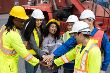 Diverse team of industrial workers joining hands in unity at shipping container yard, representing collaboration, motivation and strong teamwork in logistics and global trade environments.