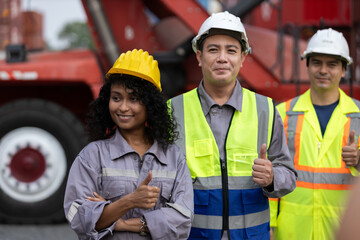 Group of diverse industrial workers giving thumbs up at container shipping yard, expressing success, teamwork and confidence in logistics, supply chain and safe working environments.